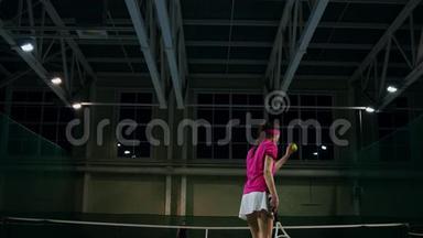 一个穿着粉红色T恤和白色裙子的女人在网球比赛中打球。 网球运动员学会打球